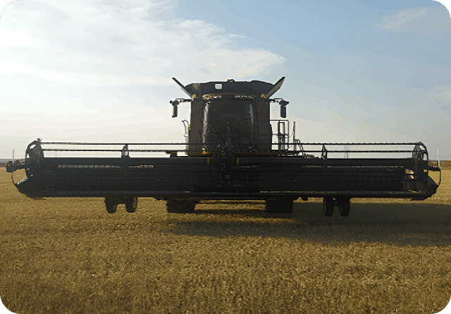 A large combine harvester working in a field during sunset.