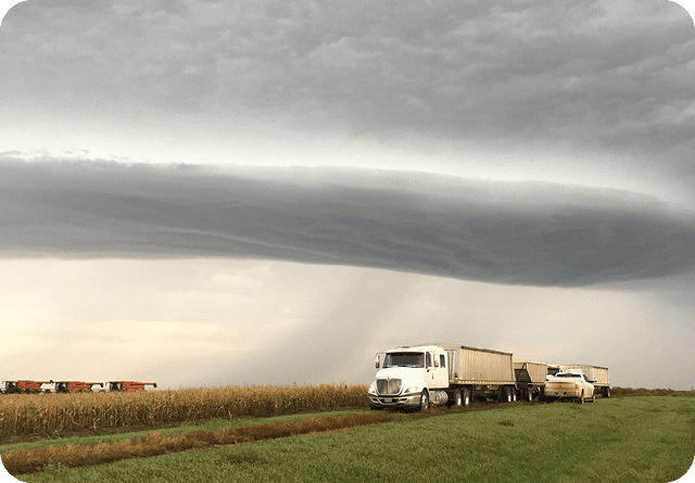 A tornado funnel cloud forming near a truck on a rural road.