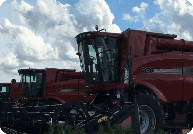 Red agricultural machinery under a partly cloudy sky.